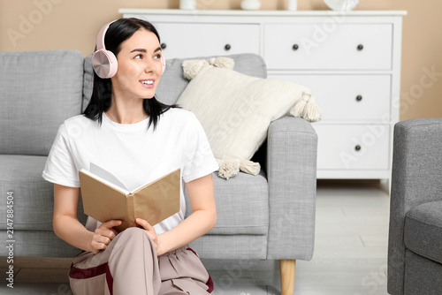 Young woman in headphones listening to audiobook at home