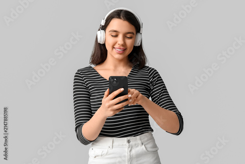Happy young woman with mobile phone and headphones listening to audiobook on ...