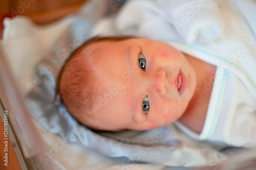 Photography Newborn baby with wide eyes looks up at camera