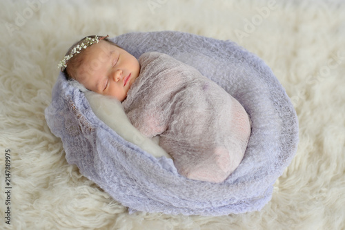 Peaceful newborn baby wearing flower headband sleeps