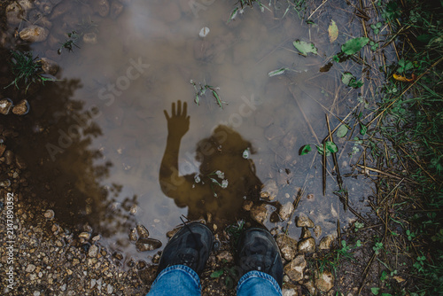 Person looking at their waving reflection in puddle