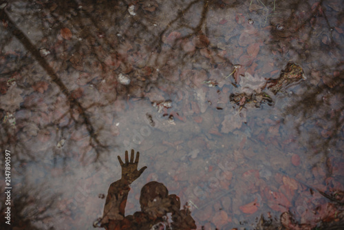 Принти на полотні Person's reflection waving in an autumn puddle