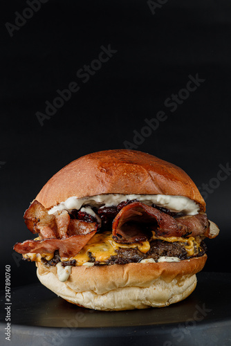Bild auf Leinwand Gourmet bacon cheeseburger against a black background