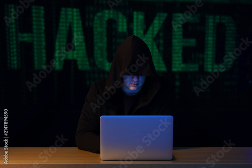 Hacker with laptop at table...