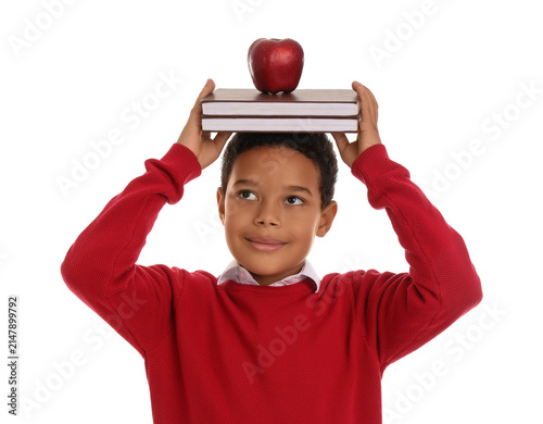 Little African-American schoolboy with books and apple on white background