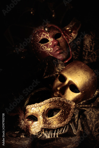 Golden carnival masks on a dark background.