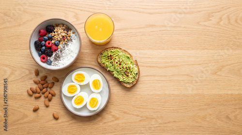 High-Protein Breakfast Flat Lay with Greek Yogurt Parfait, Eggs, Avocado Toast and Orange Juice on Oak Table