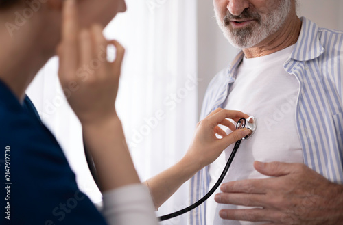 A private healthcare worker for an elderly man uses a digital tablet to monitor the patient's health at home, providing care and checking his physical condition.