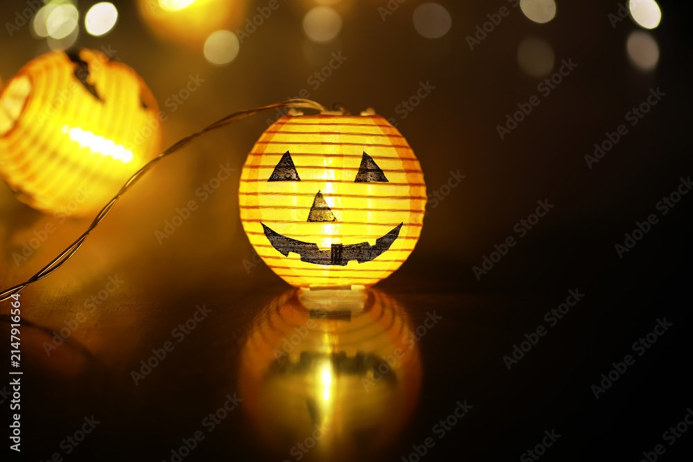 Obraz premium Festive Halloween Jack-O'-Lantern Pumpkin Lantern Glowing in Dark with Bokeh Background