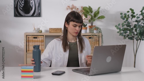 Young woman teleworking using a laptop in her home office