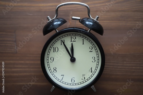 Foto Vintage Black Alarm Clock on Wooden Table - Retro Timekeeping Concept