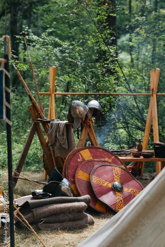 Картината върху платно Shields and helmets lie on the ground next to a wooden stand inside a medieval reenactment camp