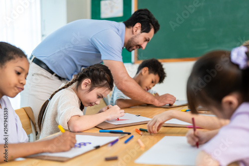 Group of diverse kids coloring paper in classroom at elementary school. 