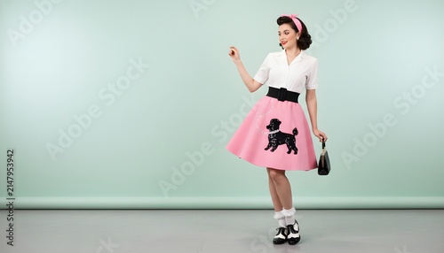 Stylish vintage woman in poodle skirt posing against mint green background for classic 1950s fashion concept with copy space