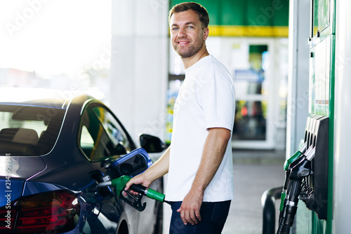 Foto Man filling up car with gasoline at a fuel station, showing everyday task of veh