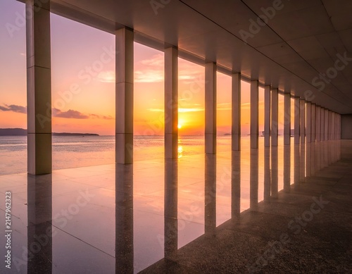 Architectural hallway frames sunset over ocean, reflecting on polished floor
