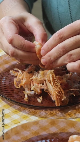 Vertical video. Food prep. Female hands peeling boiled tiger shrimp. Eating seafood.