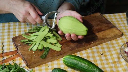 Food prep. Woman peeling ripe avocado for making summer diet vegetable salad