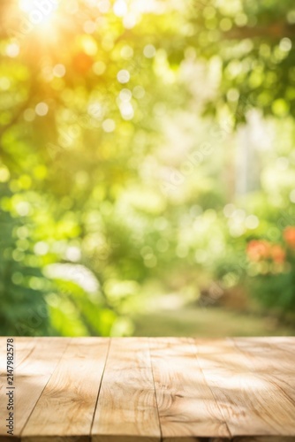 Empty Wooden Table with Blurred Green Garden Background and Sunlight.