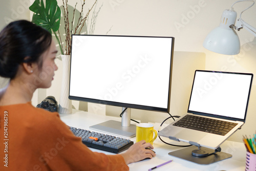 Creative designer focused on her project using a graphic tablet and dual monitors. Bright workspace with a contemporary setup and an inspiring atmosphere