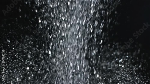 Shimmering silver glitter particles falling against a dark background for festive luxury design