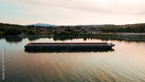 Fotografie An empty river transport barge on the Danube River during a sunset