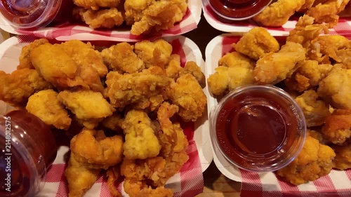 Top view of crispy popcorn chicken served in takeaway boxes with barbecue dipping sauce at a Thai night market. Freshly fried golden chicken bites prepared for street food lovers. Perfect fast food sn