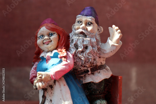 Dettaglio in primo piano di una coppia di vecchie statuine da giardino in miniatura raffiguranti gnomi o personaggi folcloristici colorati posizionati all'esterno