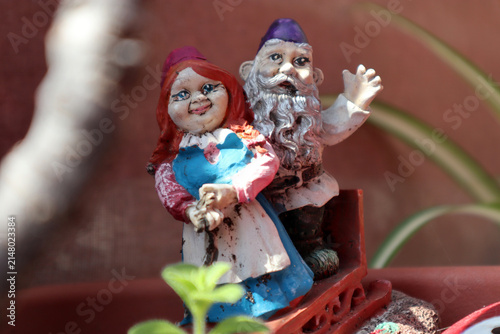Dettaglio in primo piano di una coppia di vecchie statuine da giardino in miniatura raffiguranti gnomi o personaggi folcloristici colorati posizionati all'esterno