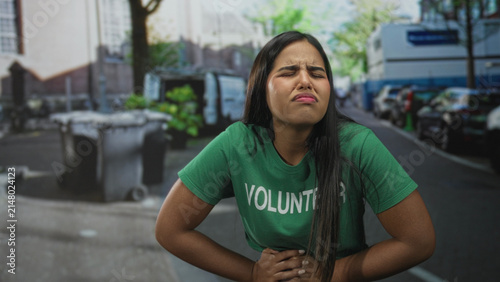 Cuadro en lienzo Young hispanic woman volunteer clutching stomach with hands and grimacing on a street; nausea distress