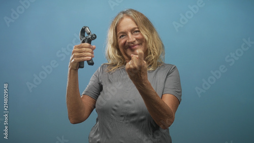 Foto Woman blonde wearing gray tee holding hand exerciser and showing middle finger to camera in studio; playful defiance strength