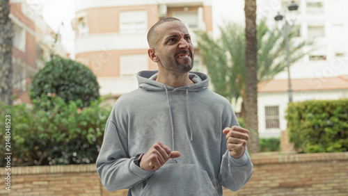 Obraz na płótnie Man checks smartwatch on wrist while adjusting the band on street, glancing down and lightly clenching fist; waiting anticipation