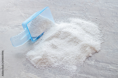 Household chemicals. Washing powder in plastic spoon on grey background