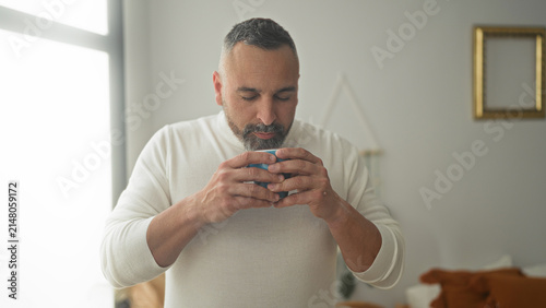 Foto Man holding a mug with both hands, eyes closed while savoring coffee in a building; morning ritual contentment