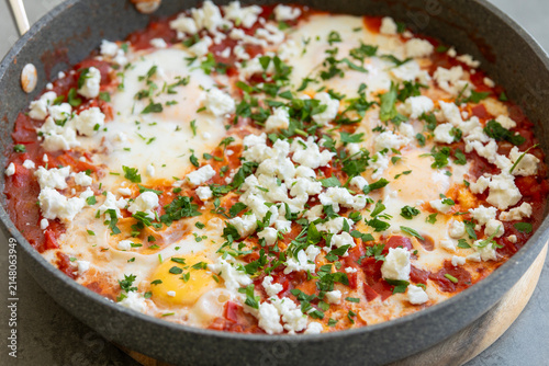Traditional Middle Eastern Shakshuka Eggs Poached in Tomato Sauce Topped with Crumbled Feta and Parsley