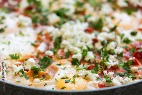Traditional Middle Eastern Shakshuka Eggs Poached in Tomato Sauce Topped with Crumbled Feta and Parsley