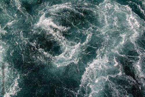 Dark turquoise swirling frothy water close-up. Pristine clear Waikato River, New Zealand flowing from Lake Taupō Control Gates, supporting downstream hydroelectric generation.