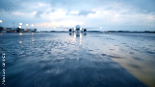 Wet runway surface with vehicles and lights under cloudy sky