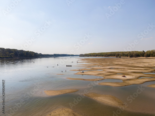 People sunbathing and swimming on exposed sandbars on the Danube River during extreme low water levels and heatwave caused by global climate change near Apatin. APATIN, SERBIA - AUGUST 4, 2026
