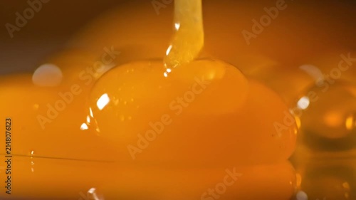 Close up of golden liquid pouring onto spherical objects with glossy finish