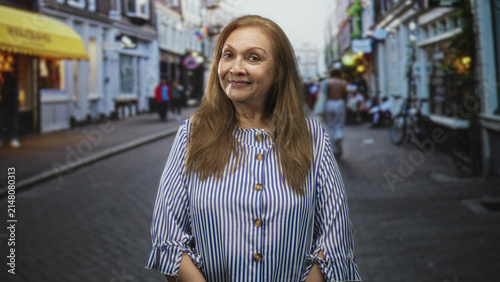 Woman with visible face looking to the right on a cobbled street wearing striped blouse; curiosity memory.