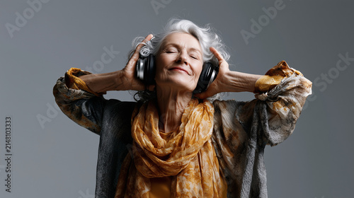 Elderly person enjoying music while listening to headphones indoors. Senior woman using headphones