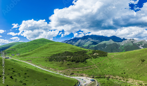 Canvas Print Aerial view of a scenic winding road passing through a lush green mountain valle