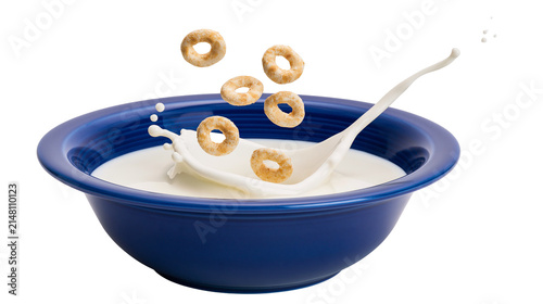 Round cereal rings splashing into blue bowl of milk with spoon, isolated on transparent background