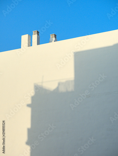 Fachada de edificio blanca con chimeneas y un cielo azul