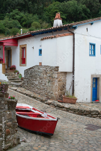 Traditional house and red fishing boat at Tazones, Asturias, Spain
