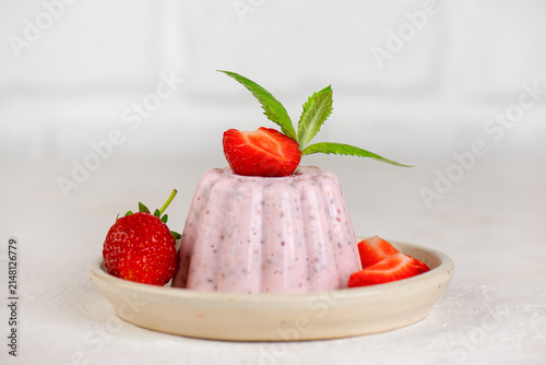Minimal food still life with homemade strawberry chia dessert and fresh mint leaves on a light table.