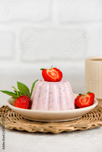 Minimal food still life with homemade strawberry chia dessert and fresh mint leaves on a kitchen table. Vertical orientation.