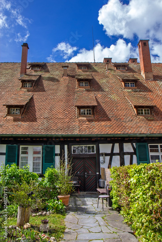 Steep red clay tile roof of a traditional half-timbered house in Triberg, Black Forest, Germany, featuring dormer windows, brick chimneys, and classic regional architecture.