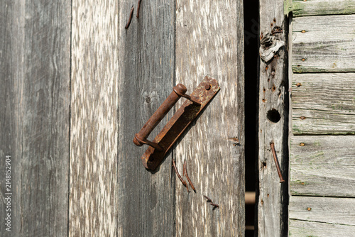Foto An old wooden front door to a country house with a rusty iron handle